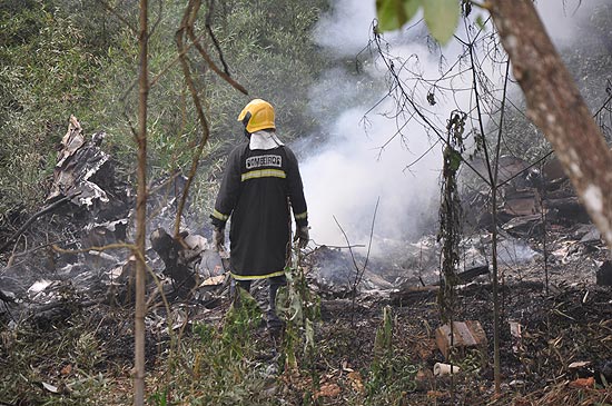 Bombeiro observa os destroços do avião bimotor que caiu em Juiz de Fora (MG) matando oito pessoas