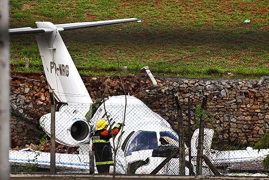 Bombeiro observa jato que derrapou e caiu em um terreno no aeroporto de Congonhas, em SP