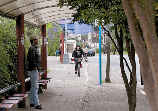 Ciclista pedala em trecho da ciclovia da Faria Lima que passa no meio de ponto de ônibus