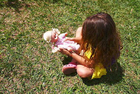 Menina de seis anos brinca com sua boneca em frente na periferia de Ribeirão Preto (SP)