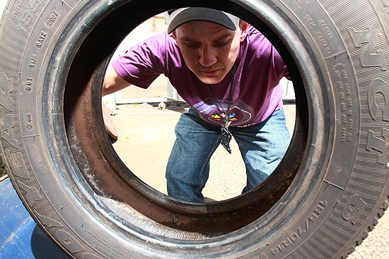 O agente Sidney de Oliveira inspeciona pneu em garagem em Ituverava (SP)