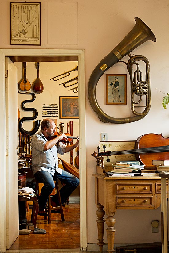 Roberto Holz toca violino em sua oficina; ex-arquiteto produz peas raras em sobrado na Lapa (zona oeste)
