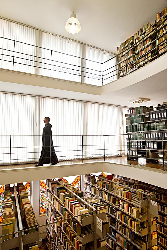 Monge caminha entre os livros da biblioteca da abadia So Geraldo, na zona oeste da capital