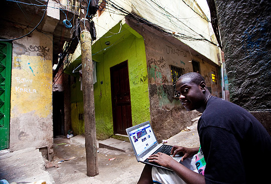 Vinícius de Lima, 19, usa o laptop da irmã na favela da Rocinha, no Rio de Janeiro