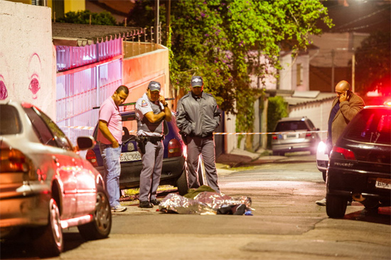 Policiais e familiares observam corpo de homem morto a tiros no Jardim das Bandeiras, zona oeste de SP