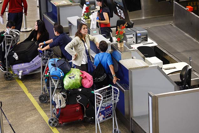 Passageiros despacham malas no aeroporto internacional de Guarulhos. Nova resolucao da ANAC limita de 32 para 23 kg