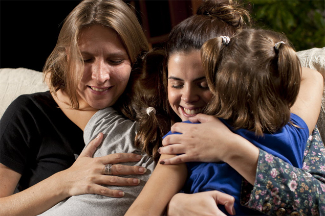 Anny (de cinza) e Amanda abraçam sua mãe (esq.) e a mulher que as socorreu do choque