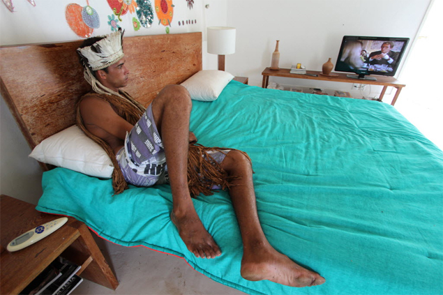 Índio tupinambá, um dos 70 que invadiram hotel de luxo na Bahia, assiste à TV a cabo em bangalô