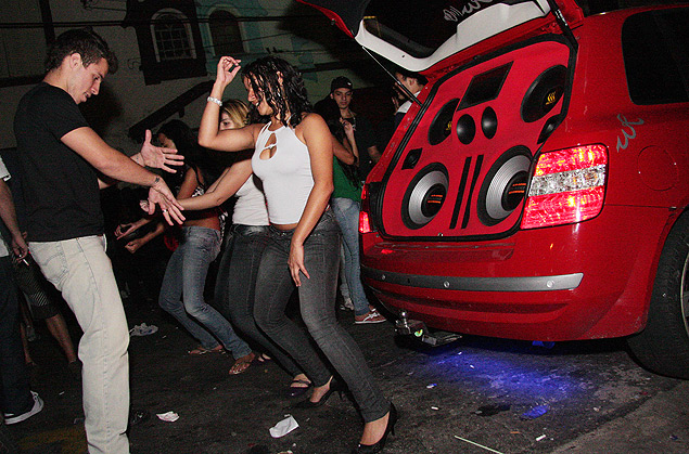 Jovens dançam ao lado de carro com som alto estacionado em rua na zona sul de São Paulo; dono do carro poderá ser multado