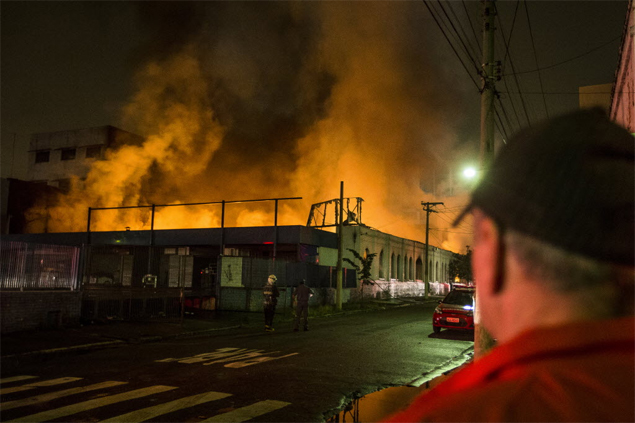Homem observa incêndio de grande proporção em shopping popular no <br>Brás, na região central de São Paulo