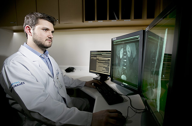 Thiago Moreira Cruz, 28, em uma sala de laudos médicos de tomografia computadorizada. Ele faz residência em radiologia