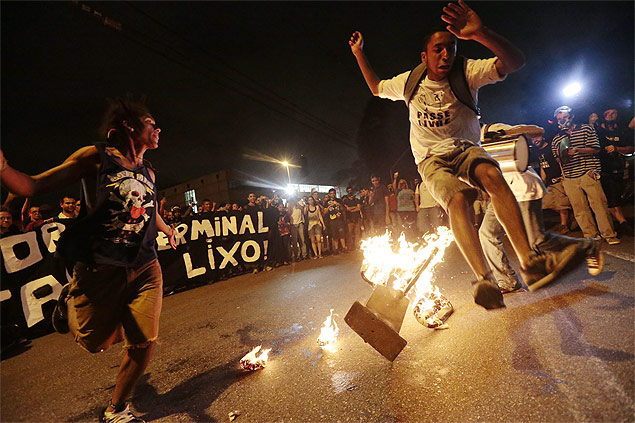 Manifestantes pulam catraca queimada durante protesto do MPL na estrada do Campo Limpo, na zona leste de So Paulo