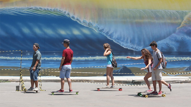 Skatistas passam diante de mural de festival de surfe no parque do Ibirapuera, na zona sul de SP