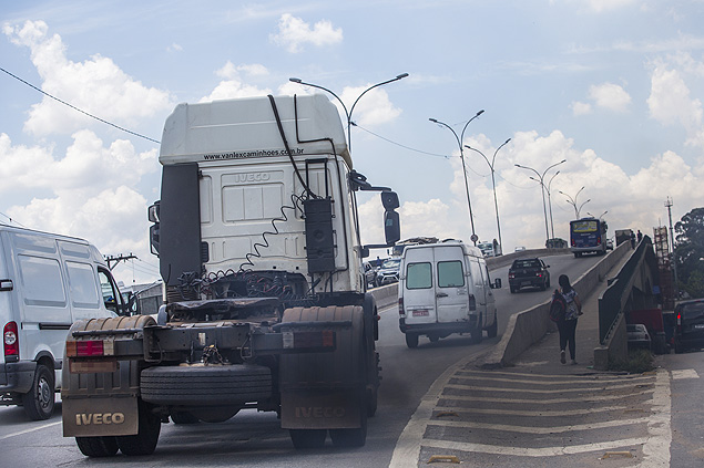 Caminho solta fumaa preta enquanto pedestres atravessam a ponte dos remdios, na marginal Tiet, em So Paulo