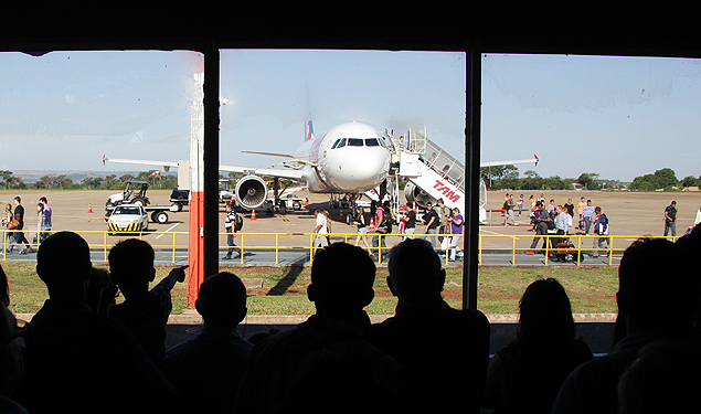 Pessoas observam o desembarque de passageiros no ptio dos avies do aeroporto Leite Lopes