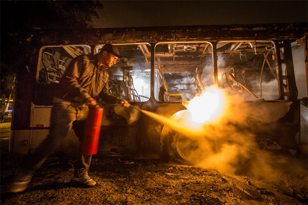 Funcionrio tenta apagar chamas em nibus incendiado na rua Jos Joaquim Gonalves, zona sul de So Paulo