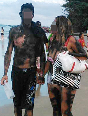 Imagem de casal de turistas manchado com tinta após pichar pedra em praia do Guarujá, em SP 