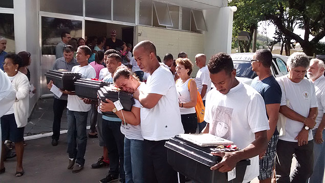 Pais das vtimas do massacre de Realengo seguram urnas com os restos mortais dos filhos