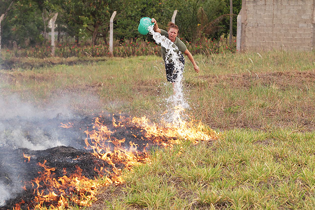 A aposentada Ivandira da Cruz, 60, tenta apagar fogo em terreno com um balde de gua