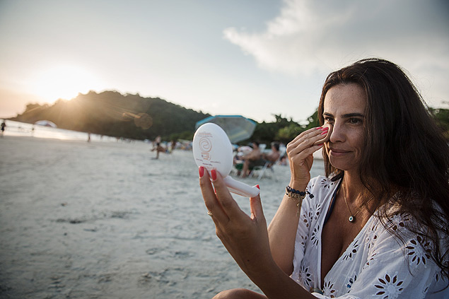 A empresria Simone Brando, 47, aplica maquiagem com protetor solar na praia Juquehy, em SP
