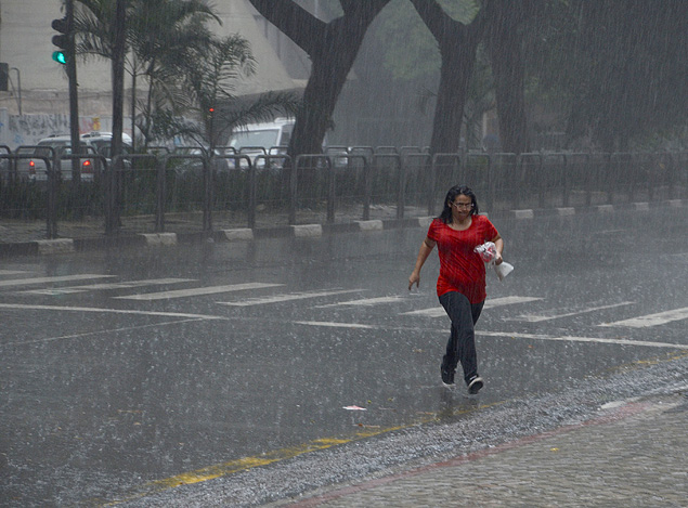Mulher atravessa a rua da Consolao, no centro de SP, sob forte chuva neste sbado (7)