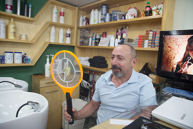O cabeleireiro Jos Mendes com a raquete que comprou para matar mosquitos aps ser infectado na Liberdade (centro)