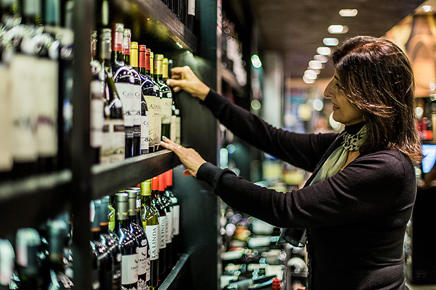 Consumidora escolhendo vinho; imposto sobre a bebida subir