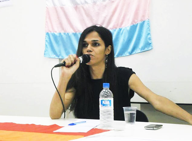 Daniela Andrade discursa em frente  bandeira do movimento transexual