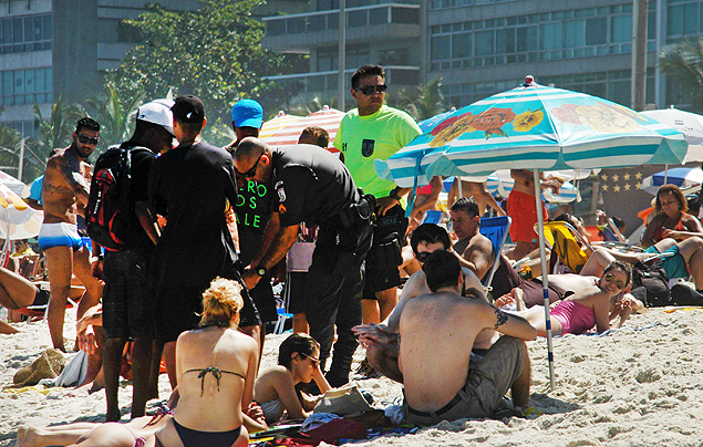 Policiais abordam adolescentes na praia de Ipanema, na zona sul do Rio