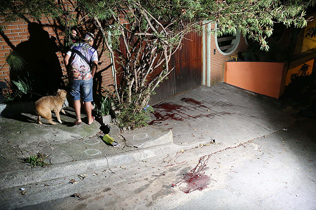 Morador observa sangue de vítimas no local dos assassinatos, em Carapicuíba (Grande SP)