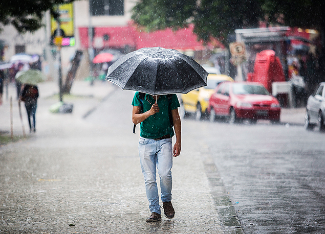 Homem caminha sob chuva forte na regio central de So Paulo