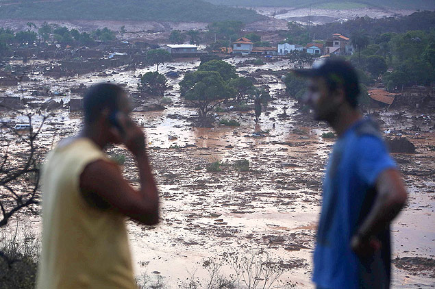 Homens buscam informaes em meio a casas destrudas pela lama aps queda de barragem