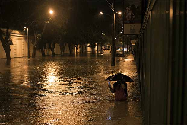 A man wades through a flooded street at the Jardim Botanico neighborhood after heavy rains in Rio de Janeiro, Brazil, Saturday, March 12, 2016. Authorities in Rio declared state of crisis after torrential rains flooded parts of the city late Saturday leaving cars, buses and residents stranded. (AP Photo/Felipe Dana) ORG XMIT: XFD106