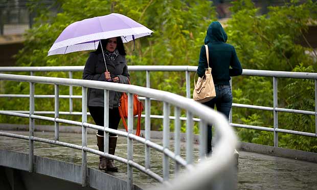 Pedestres se protegem da chuva na regio central de So Paulo; temperatura cai entre quarta e quinta-feira
