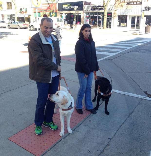 Kátia e Genivaldo passeiam por rua em Michigan (EUA) com seus cães-guia
