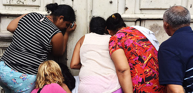 Familiares de detentos espiam pelo buraco da fechadura da cadeia pblica, em Manaus