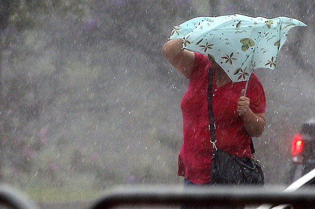 Pedestre sofre para manter guarda-chuva aberto durante forte chuva no centro de São Paulo