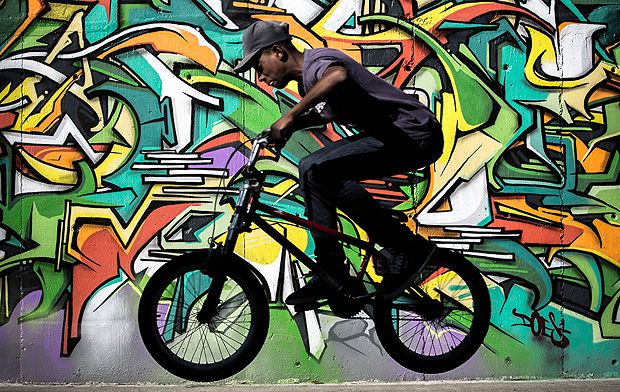 Ciclista passa por grafite na zona norte, no primeiro Museu de Arte de Rua, em projeto inaugurado pelo prefeito Doria