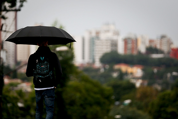 Jovem se protege da chuva na regio da av. Dr. Arnaldo; junho teve 78% mais chuva que a mdia