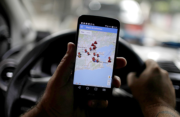Taxista mostra aplicativo "OTT - Onde Tem Tiroteio", em seu celular, no Rio de Janeiro 