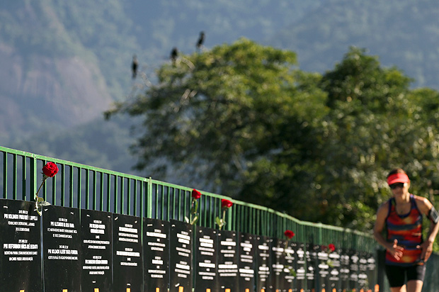Mulher caminha ao lado de quadros com nomes de policiais mortos no Rio de Janeiro 