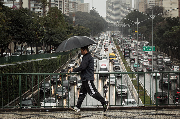 Homem caminha sob a chuva no viaduto Tutoia, na capital paulista; temperaturas caem neste domingo