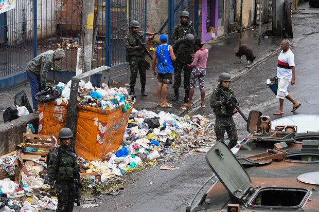 Soldiers question people during a pre-dawn crackdown on crime gangs at the Jacarezinho favela in Rio de Janeiro, Brazil, on August 21, 2017. In the third such operation in just over two weeks, marines, army soldiers, air force personnel, police and agents from the elite federal intelligence service launched raids at dawn in seven of Rio de Janeiro's most violent favelas, the Rio state security office said. / AFP PHOTO / Apu Gomes