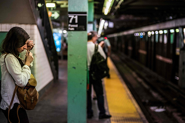 Mulher retoca maquiagem enquanto espera pelo trem em estao de metr de Nova York