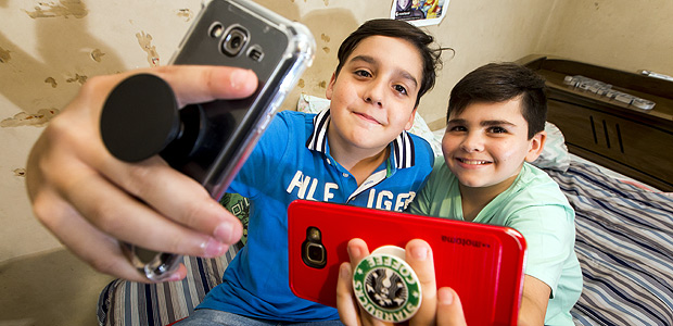 Guilherme Castro Lima e Matteo Piva (ao fundo) usam no celular o PopSocket