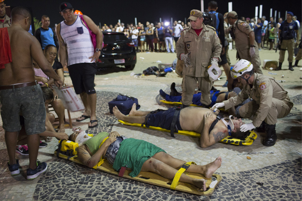 Firefighters give the first aid to people that were hurt after a car drove into the crowded seaside boardwalk along Copacabana beach in Rio de Janeiro