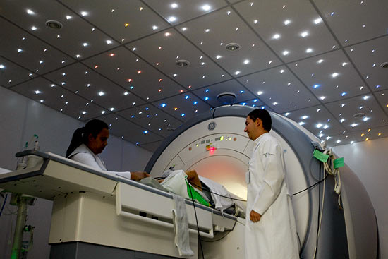 Técnicos colocam paciente em aparelho, no Instituto do Câncer