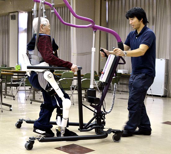 Emiko Tsunematsu, 84, à esquerda, usa robô desenvolvido pela Universidade de Tsukuba