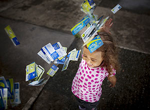 Mariana Petrosink controla tempo de banho do irmão; acima, ela brinca com cartões telefônicos que recolhe na rua