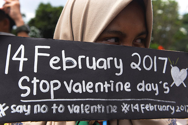 Estudante muulmana segura cartaz em protesto contra o Dia dos Namorados em Surabaya, Indonsia